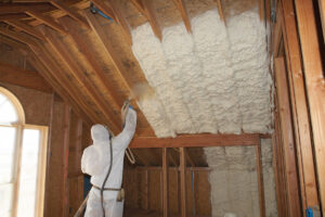 a man in a white suit spraying foam on a roof